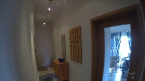 Een hal met een houten kast, een blauw tapijt en een grote spiegel aan de muur.