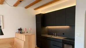 Una cocina moderna con armarios oscuros, una zona de comedor de madera y un horno empotrado.