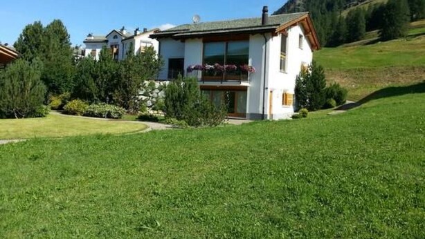 A two-story house with a balcony, surrounded by a well-maintained lawn and trees. - Chesa Ovelin by Interhome (Pontresina)