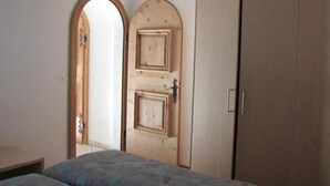 A bedroom with a bed, a wardrobe, and two doors. - Chesa Ovelin by Interhome (Pontresina)