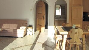 A living room with a sofa, a dining table with chairs, and wooden cabinets. - Chesa Ovelin by Interhome (Pontresina)