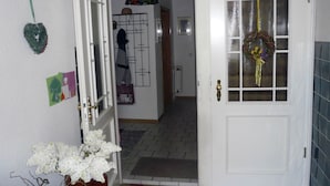 Un corridoio con una porta bianca, un tappeto decorato e un portascarpe a parete.
