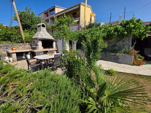 Un patio al aire libre con una parrilla de piedra, una mesa y sillas.