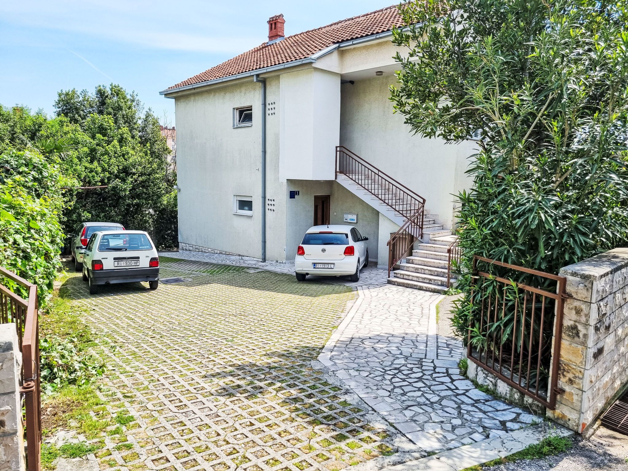 Um edifício de dois andares com um caminho de paralelepípedos e uma escadaria que leva à entrada.