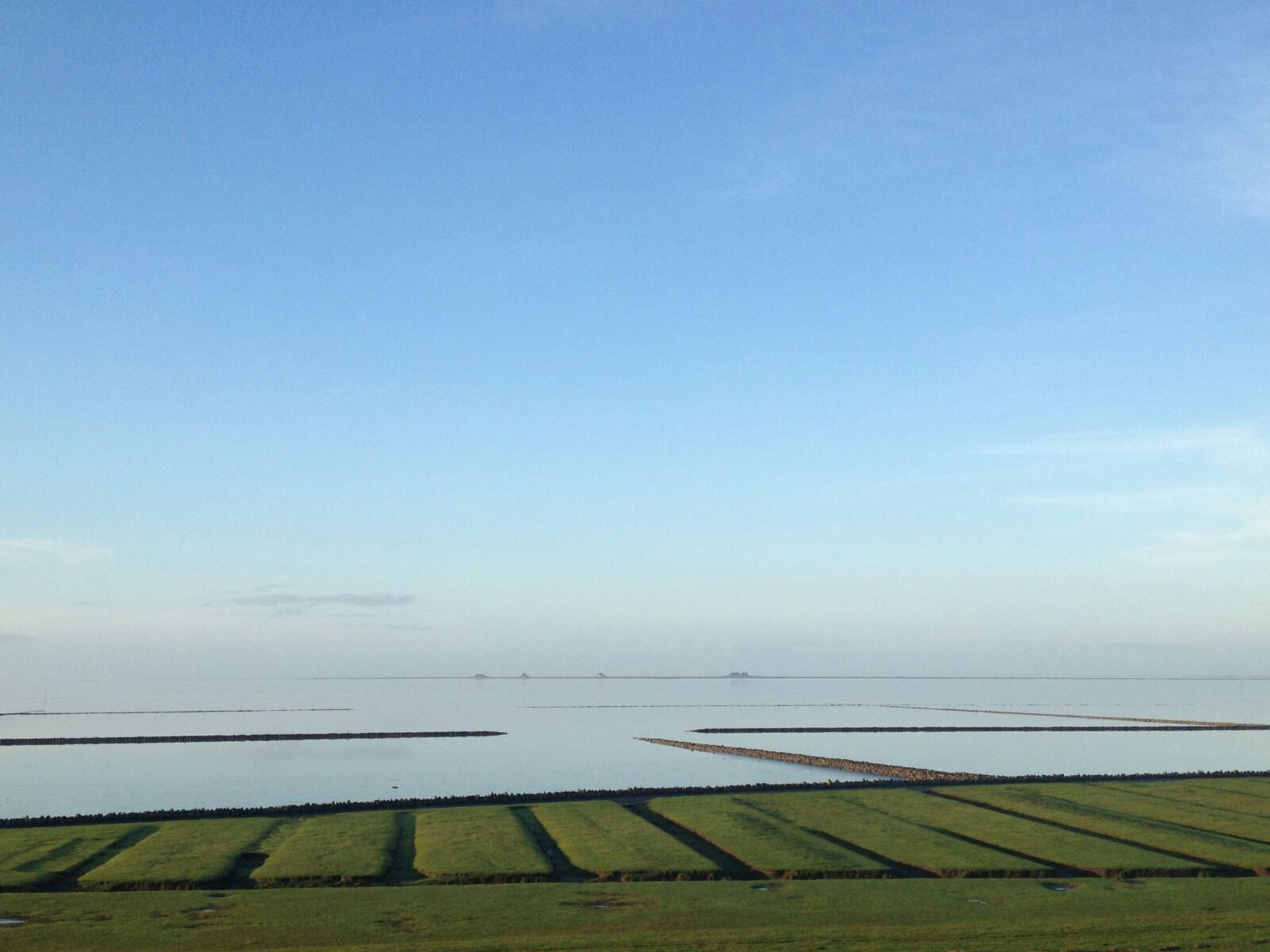 A wide view of a coastal landscape with fields and a calm sea.