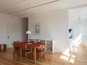 Ein geräumiger Essbereich mit einem Holztisch und Stühlen, einer weißen Pendelleuchte und einem weißen Schrank mit Geschirr.