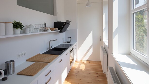 Moderni keittiö, jossa on sisäänrakennettu uuni, pesuallas ja ikkuna, josta tulee luonnonvaloa.