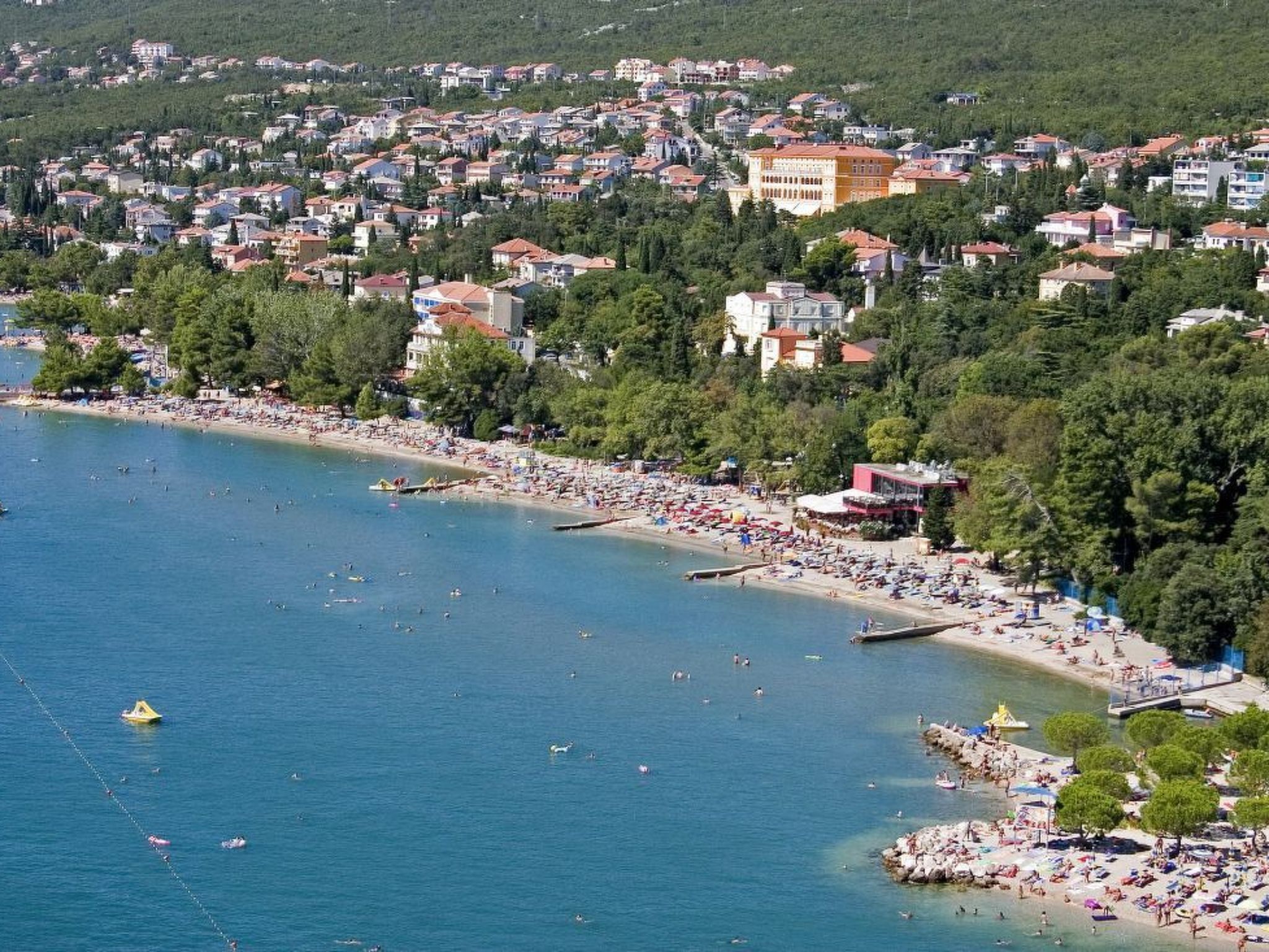 A coastal town with a beach, buildings, and greenery.