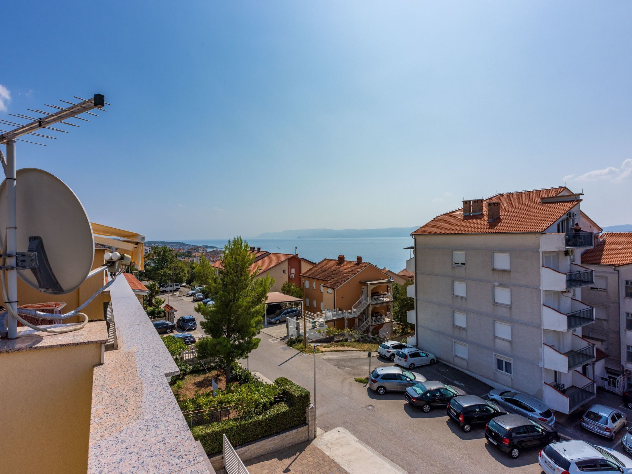 Ein Wohngebiet mit freiem Blick auf das Meer, parkgepflasterten Flächen und Gebäuden mit Balkonen.