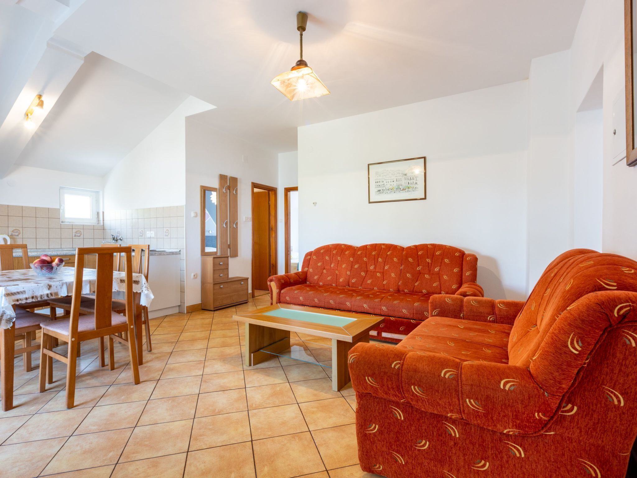 Uma sala de estar com sofá, cadeiras, mesa de centro e um espaço de jantar com mesa e cadeiras.