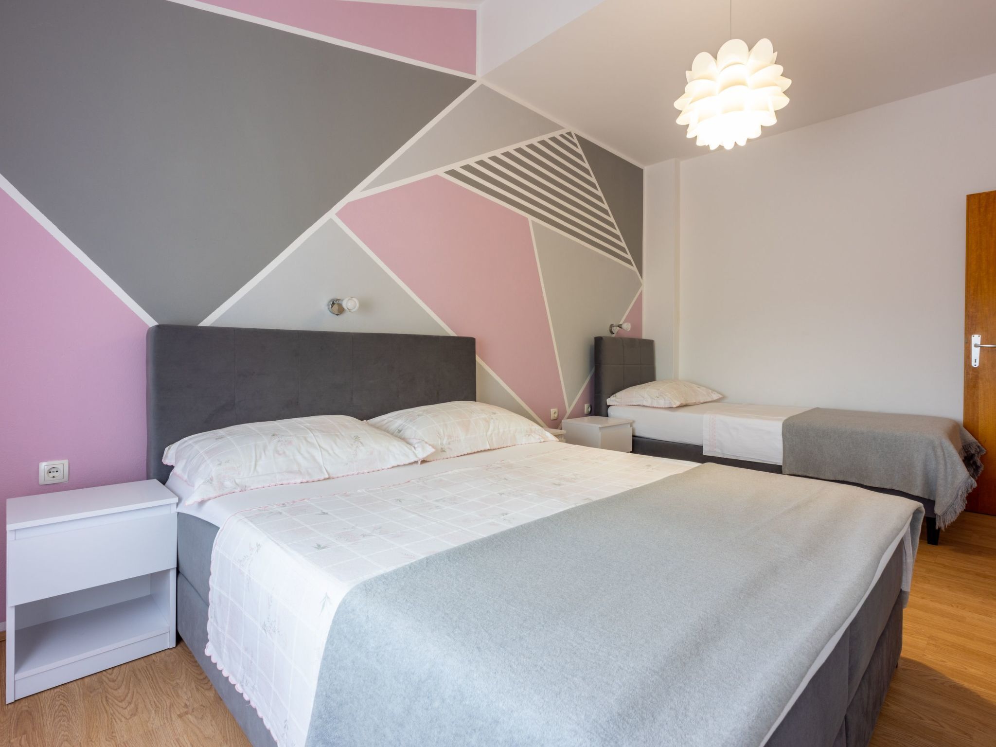 Un dormitorio moderno con una cama grande, mesitas de noche y un diseño de pared geométrico único.