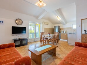 A spacious living area with a wooden bench, a dining table, and a TV. - Wohnung für 6 Personen mit Balkon und Meerblick by Interhome (Crikvenica)