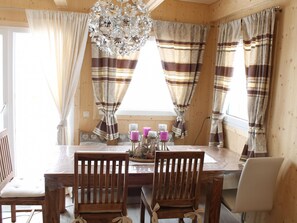 A wooden dining room with striped curtains, a chandelier, and a table set with candles. - Klippitzhimmel in Klippitztörl by Interhome (Bad St. Leonhard im Lavanttal)