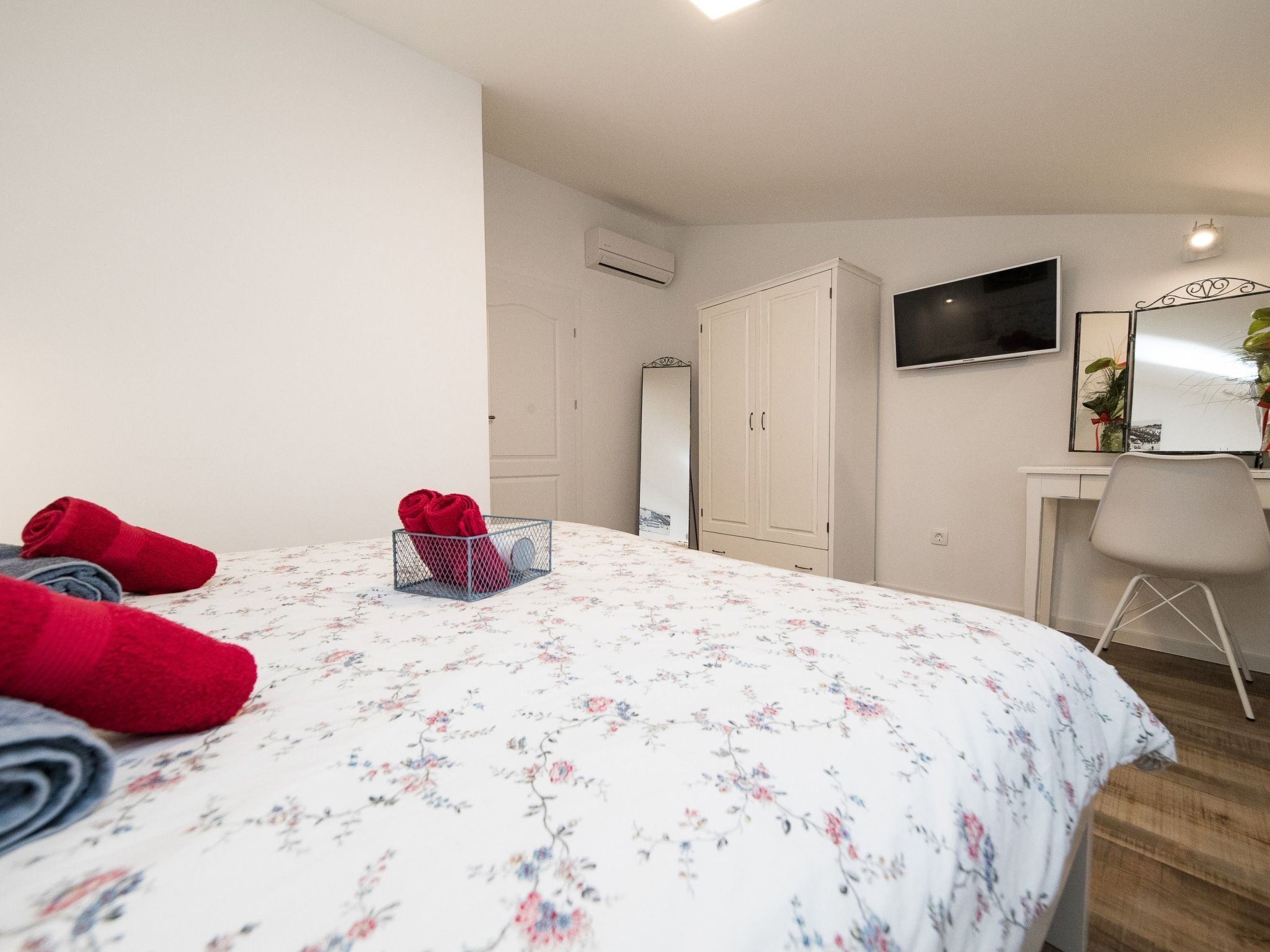 A bedroom with a bed, a desk, a chair, and a TV.