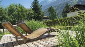 A wooden deck with two wicker lounge chairs facing a mountainous landscape. - Bio-Haus # 401 by Interhome (Neukirchen am Großvenediger)