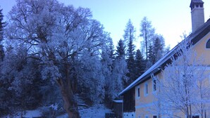 A snow-covered landscape with a yellow building and trees. - Erdgeschosswohnung in 320 Jahre altem Haus by Interhome (Mariapfarr)