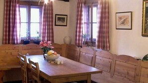 A dining area with a wooden table and benches, a vase with flowers, and two framed pictures on the wall. - Erdgeschosswohnung in 320 Jahre altem Haus by Interhome (Mariapfarr)