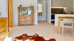 A modern kitchen with white cabinets and a wooden dining table. - Chesa Auricula by Interhome (Pontresina)