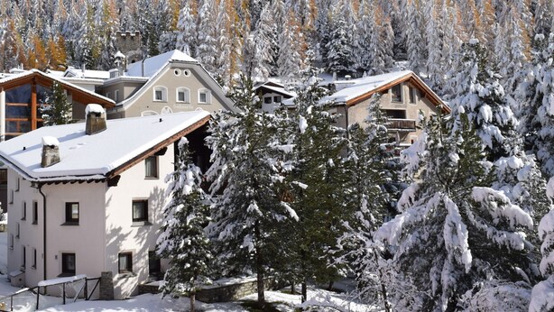 Una zona residencial cubierta de nieve con varias casas, incluyendo un edificio con un letrero que dice "Saldanella".