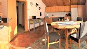 Una cocina acogedora con armarios de madera, una mesa de comedor y un microondas.