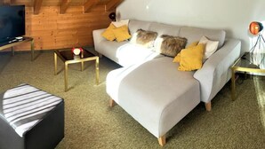 Una sala moderna con sofá, reposapiés y mesa de centro.