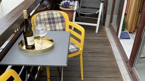 Un patio al aire libre con sillas amarillas y una mesa, una botella de vino y una copa sobre la mesa.