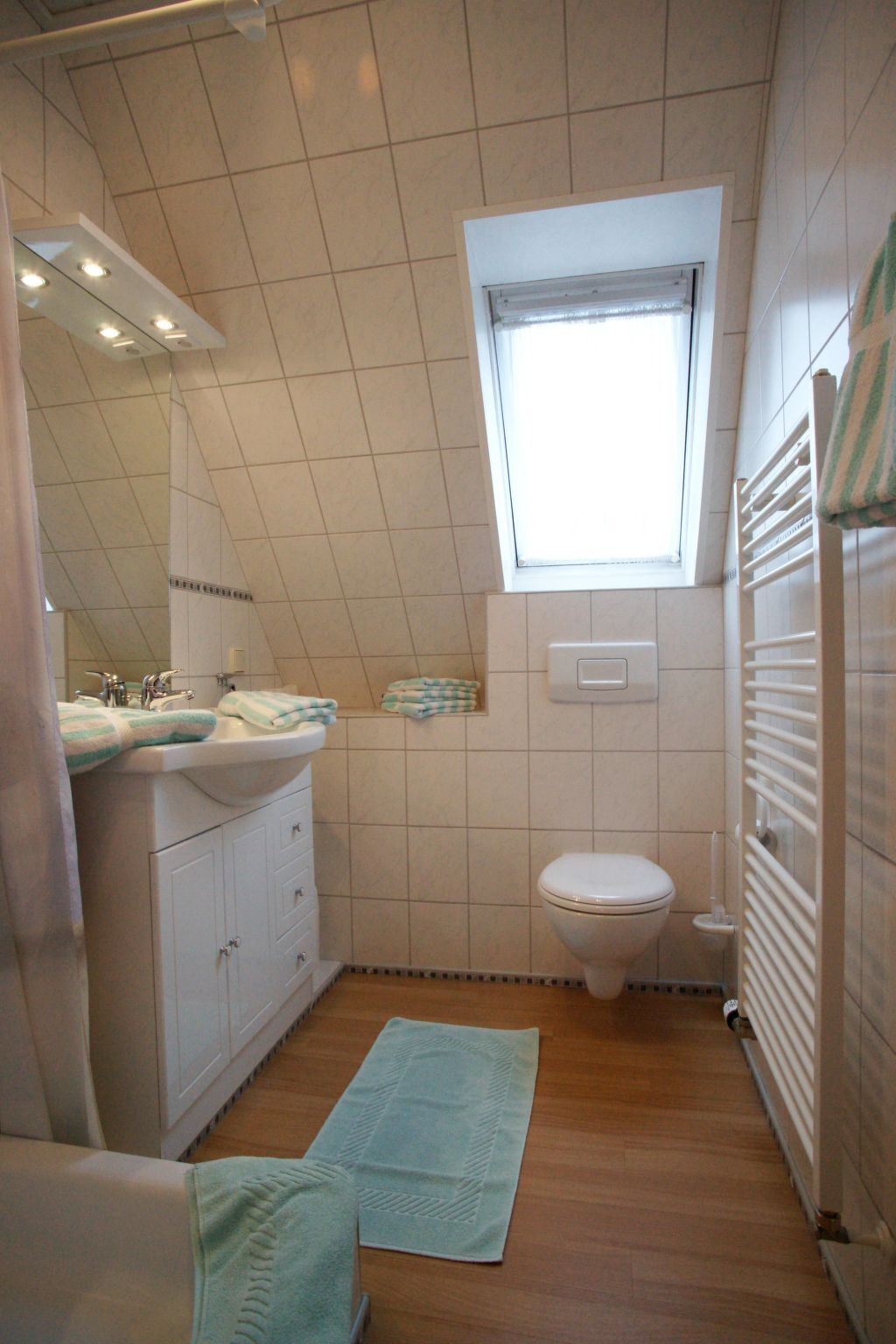 A compact bathroom with a window, a sink, a toilet, and a radiator.