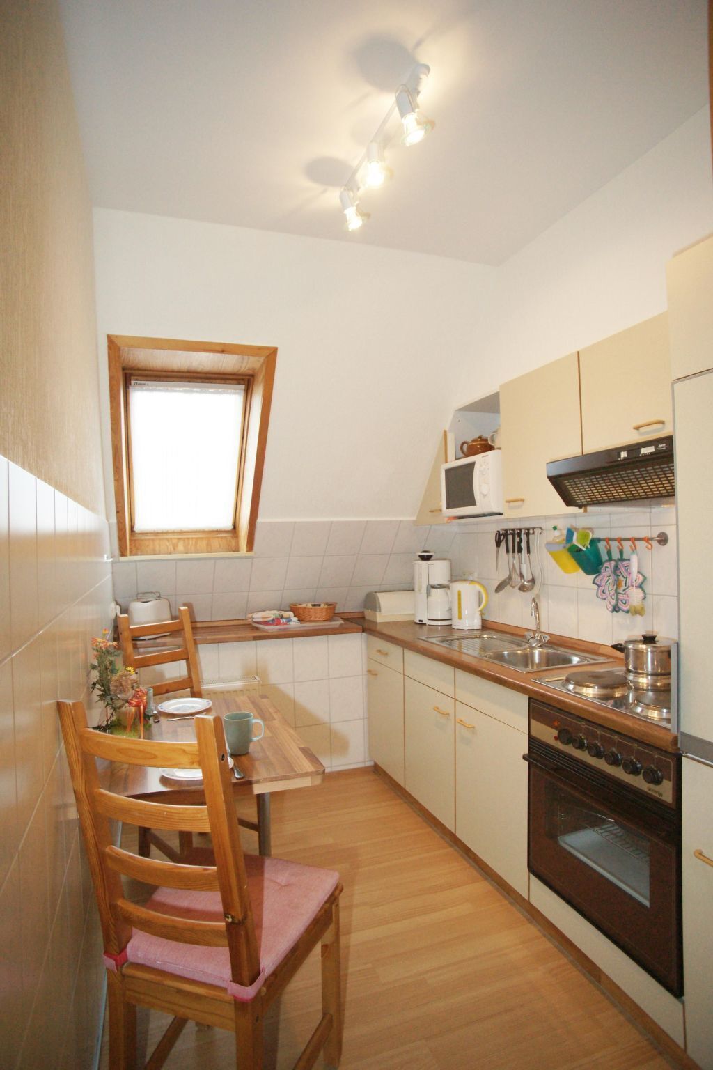 A compact kitchen with a dining area, a small window, and basic appliances.
