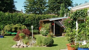 Ein gepflegter Garten mit verschiedenen Pflanzen und einem kleinen Geräteschuppen.