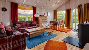 A cozy cabin with a plaid sofa, wooden dining table, and a fireplace. - Dänemark in Gelting by Interhome (Gelting)