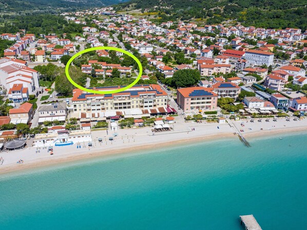 Vista aérea de un pueblo costero con un hotel destacado de varios pisos, una playa y un muelle.
