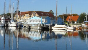 En småbåtshamn med förtöjda båtar, en blå byggnad och ett hus med rött tak.