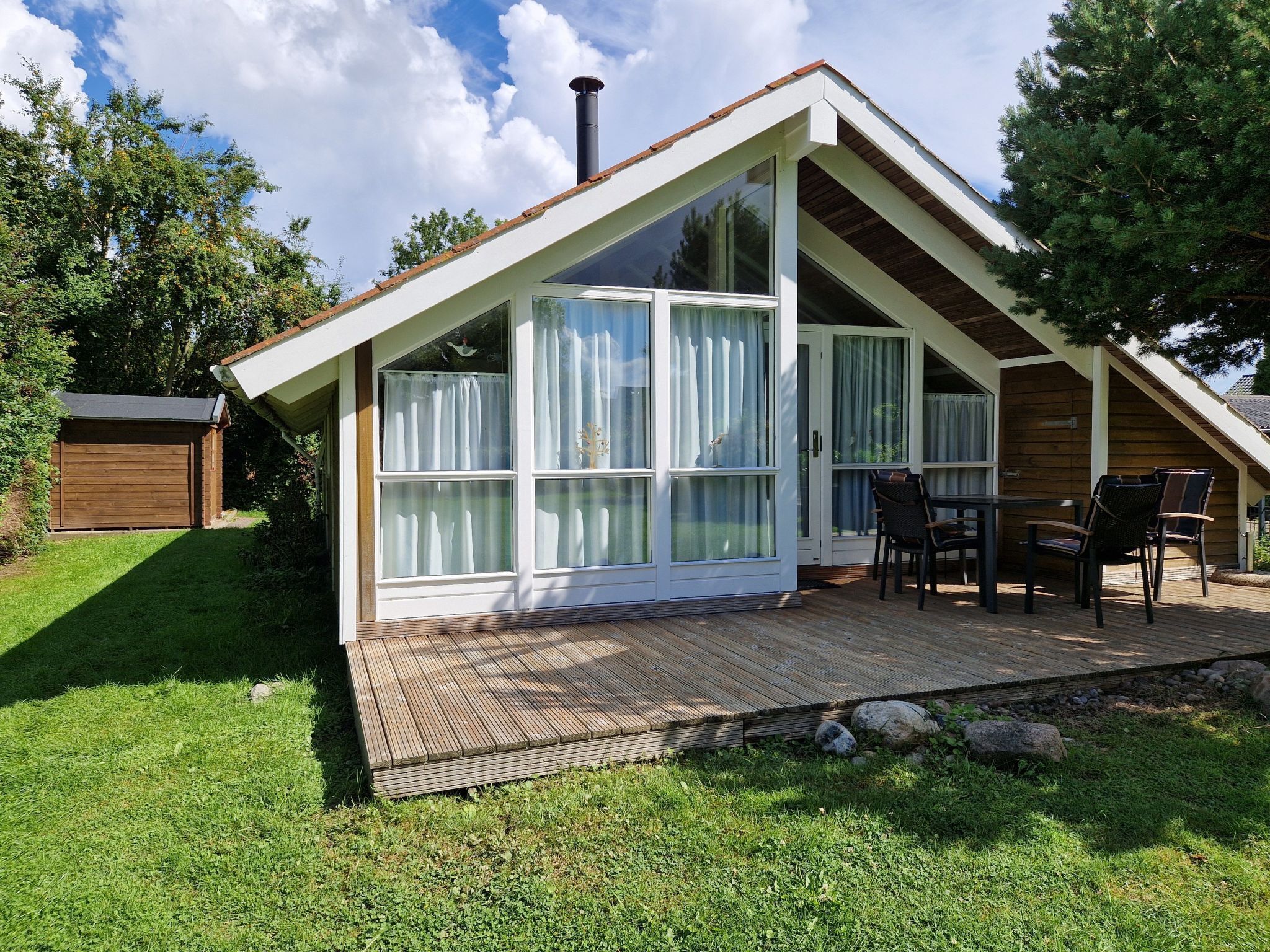 A modern house with a sloped roof, large windows, and a wooden deck.