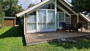 Ett modernt hus med ett sluttande tak, stora fönster och en träaltan.
