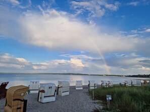 A beach with white wicker chairs and a signpost. - Vacation home Buhr by Interhome (Brodersby)