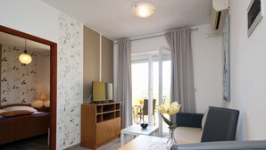 Una moderna camera d'albergo con un letto, un armadio in legno, un tavolo da pranzo con un vaso di fiori e vista sull'esterno.
