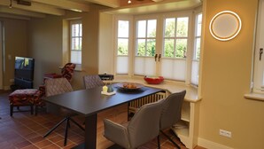 Un espace repas comprenant une table, des chaises et une fenêtre donnant sur un paysage verdoyant.