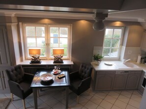 A compact kitchen with a dining table, two chairs, a window with a view, and a small sink. - Heefwai - H2W6 - in Morsum by Interhome (Archsum)