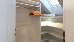 Ein begehbarer Kleiderschrank mit offenen Regalen und einer Holzkleiderstange.