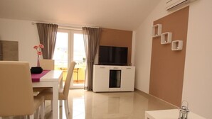 A modern living room with a dining area, a TV, and a small table with a lantern. - Gorica II A2+2 br.8 by Interhome (Krk/Baška)