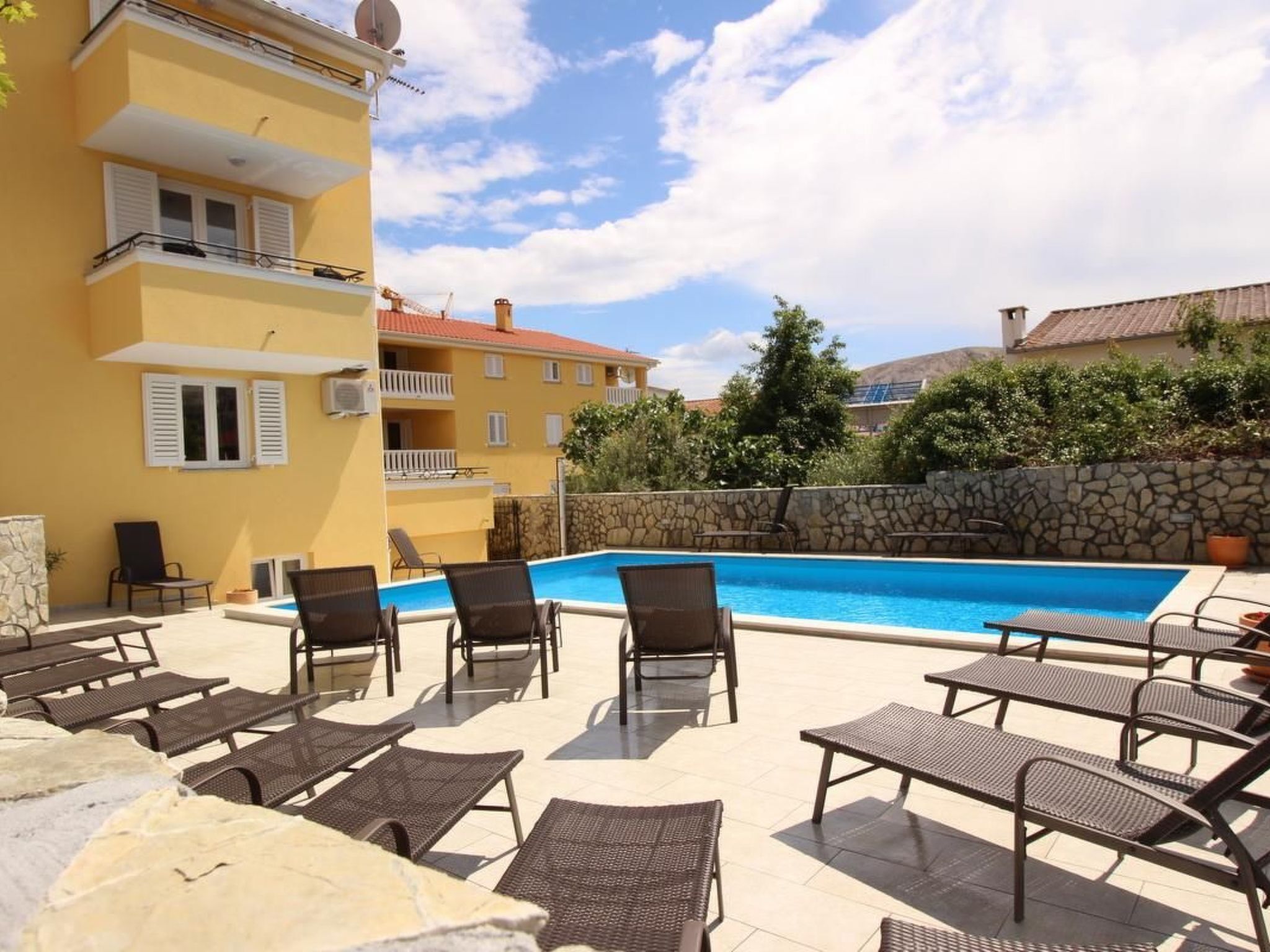 Zona de piscina con sillones de descanso y una pared de piedra.