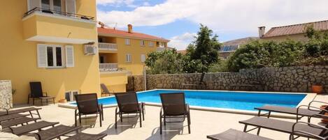 Zona de piscina con sillones de descanso y una pared de piedra.