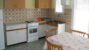 Une cuisine de taille réduite, dotée de meubles en bois, d’une cuisinière, d’un évier et d’une table à manger avec des chaises.