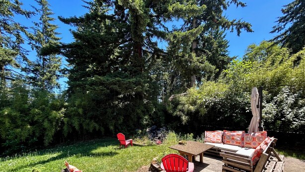 Un patio al aire libre con una silla Adirondack roja, un banco de madera y una zona de estar acolchada.