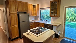 Cocina con alacenas de madera, un refrigerador, una estufa y una ventana con vista a follaje.