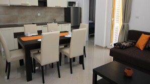 Een moderne keuken met witte kastjes, een eettafel met stoelen en een zwart aanrecht.