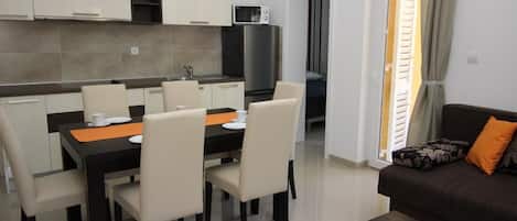 A modern kitchen with white cabinets, a dining table with chairs, and a black countertop.