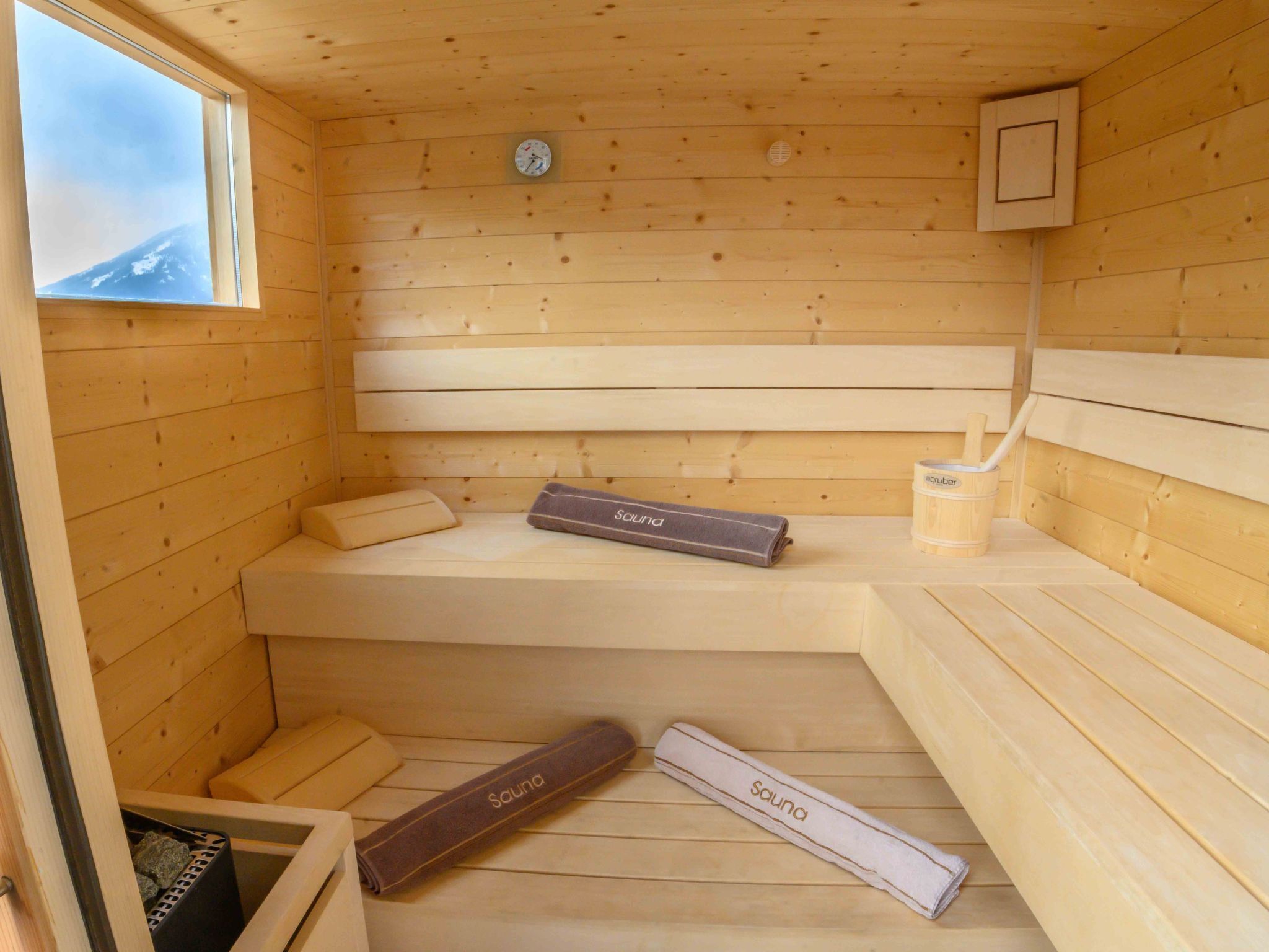 A sauna room with wooden walls, benches, and a clock.
