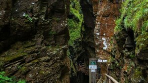 Un canyon étroit avec une passerelle en bois et un ruisseau.