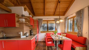 Une cuisine moderne avec des meubles de rangement rouges, un îlot central en bois et un coin repas doté de sièges rouges.